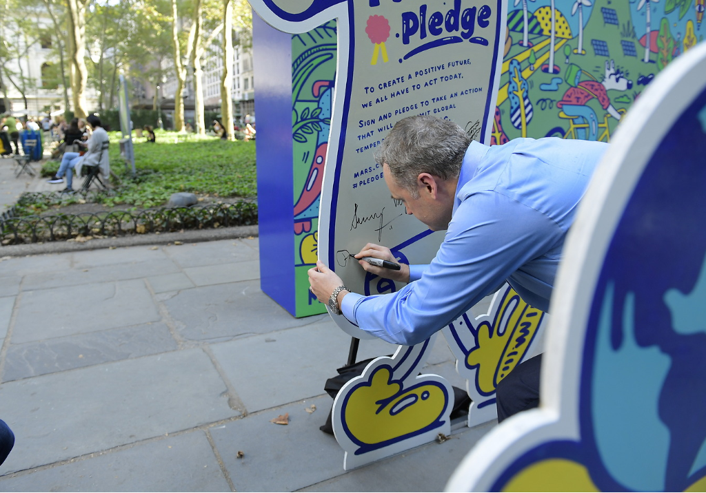 Man signing poster that looks like a contract and says