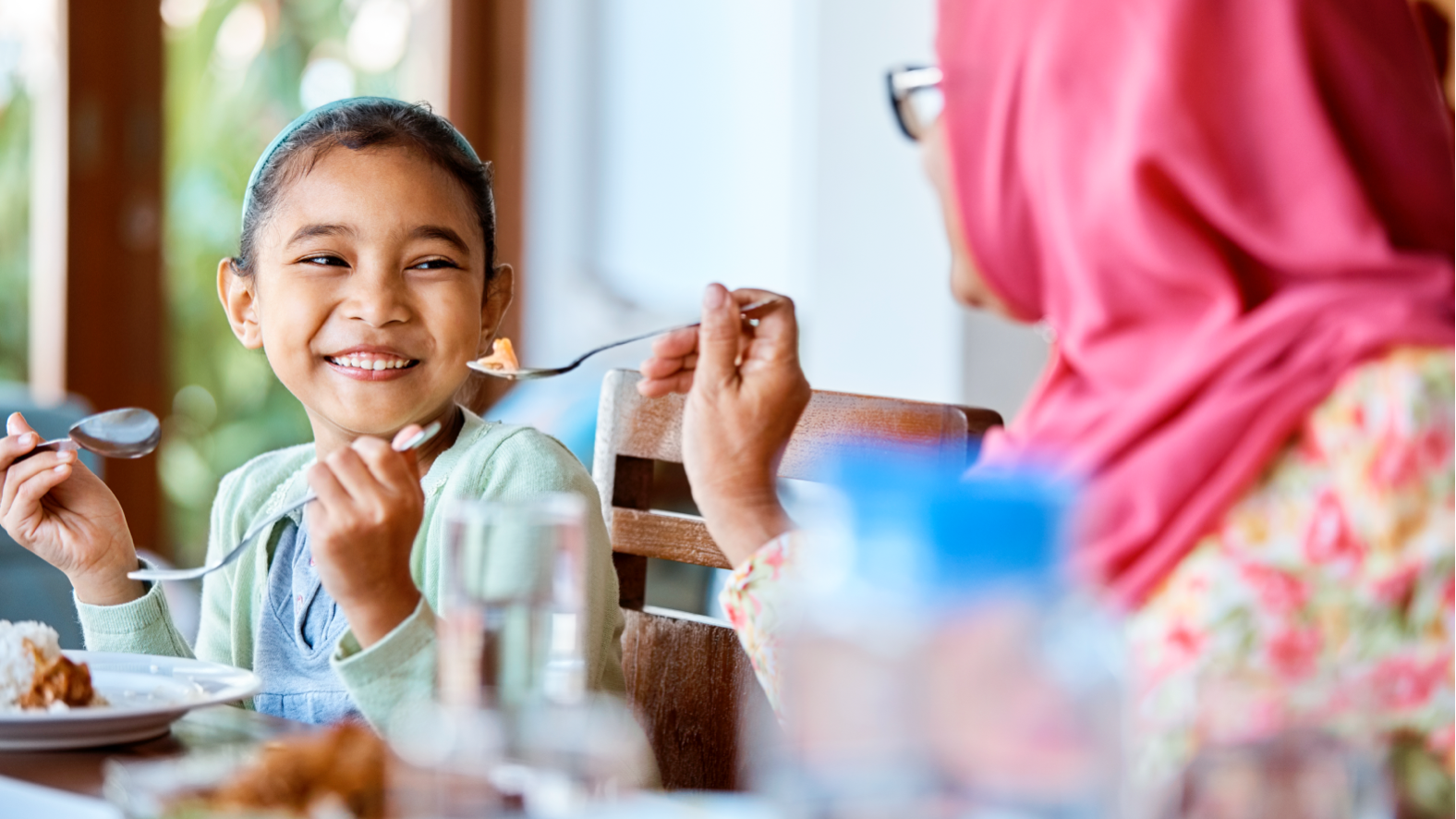 Image of smiling child being fed by mother